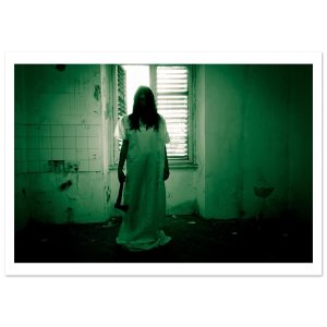 A dark and unsettling horror photograph featuring a female figure in a long white gown standing in an abandoned interior.