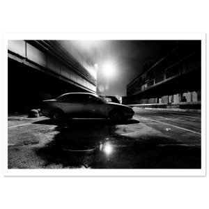 dramatic black and white night photograph of an abandoned car parked beneath an industrial overpass.