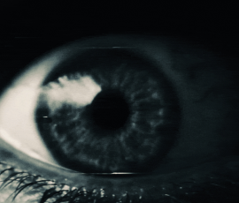 Close-up of a woman's eerie eye, framed in shadow, radiating a haunting and unsettling presence