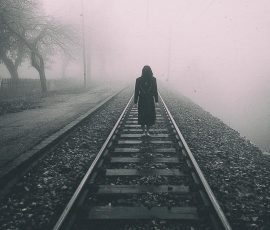 Žena u crnoj haljini u maglovitoj horor sceni.