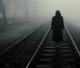 Figure walking on foggy railway tracks